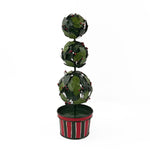 A tole metal three tiered holly topiary ball centerpiece with a striped red and green pot forming the base. 