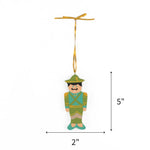 Blue hand painted wooden nutcracker Christmas ornament on a white background with dimension arrows indicating 5" by 2"