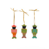Back view of three Festive hand-painted wooden nutcracker Christmas ornaments featuring colorful soldier designs and gold hanging cords for decorating.