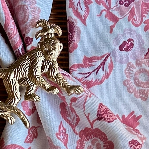Accessorized view of the East of the Sun red chinoiserie cloth dinner napkin with gold monkey metal napkin ring