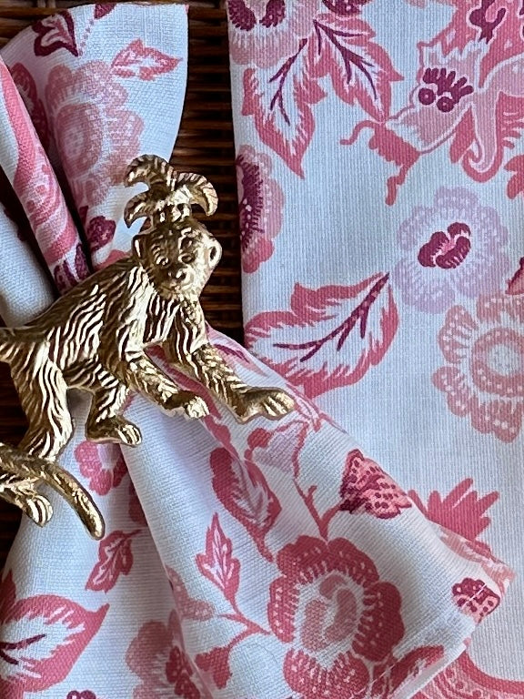 Accessorized view of the East of the Sun red chinoiserie cloth dinner napkin with gold monkey metal napkin ring
