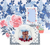 an american garden party place setting with a white plate, floral menu card, floral  placemat, floral place card and a blue and white floral paper table runner