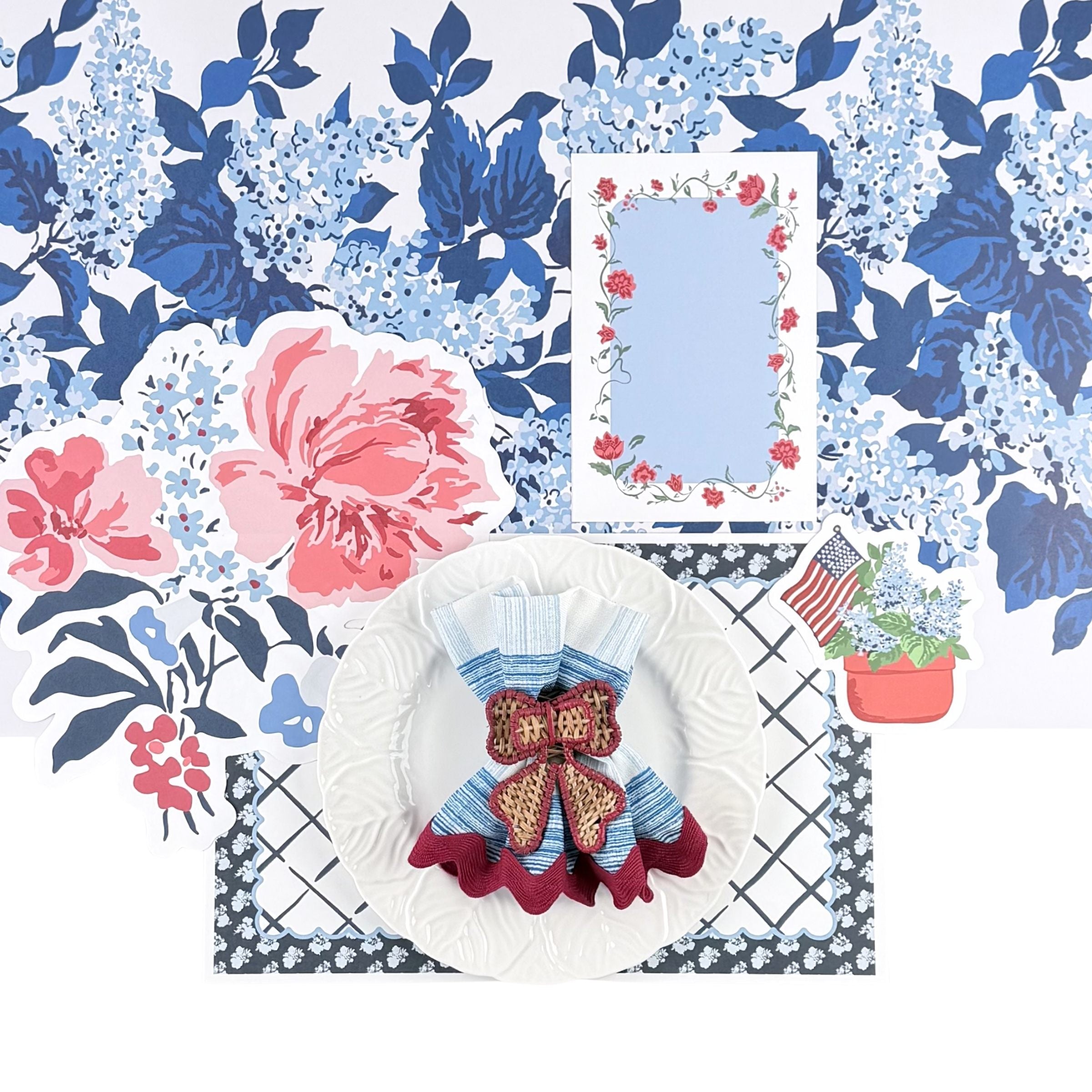 an american garden party place setting with a white plate, floral menu card, floral  placemat, floral place card and a blue and white floral paper table runner