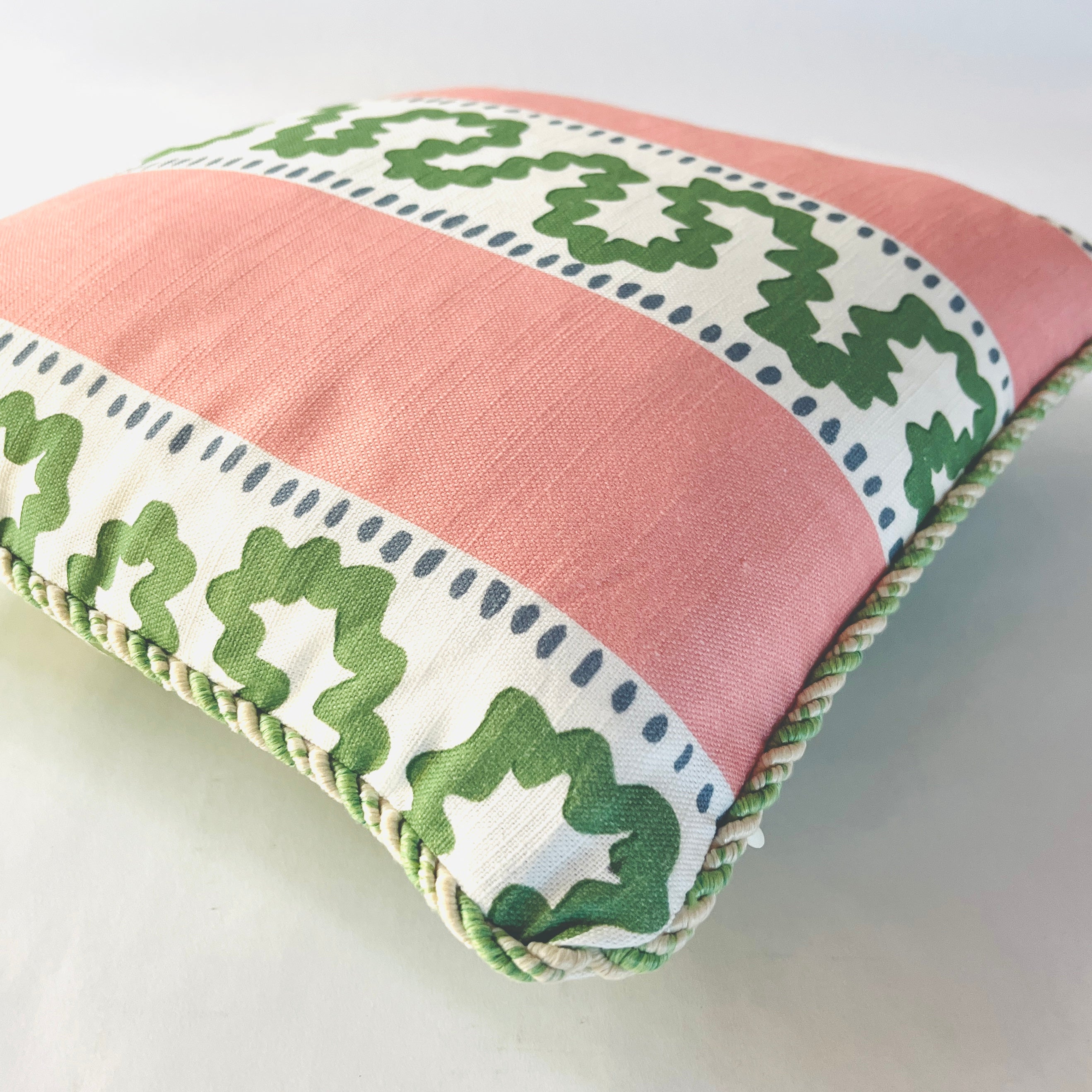 Close-up of Bahama Court striped accent pillow showing blush pink fabric, green pattern, and twisted cord trim