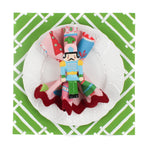 Island House square mid green paper placemats in a white background. A white plate is placed on top of it with a cloth and a nutcraker napkin ring