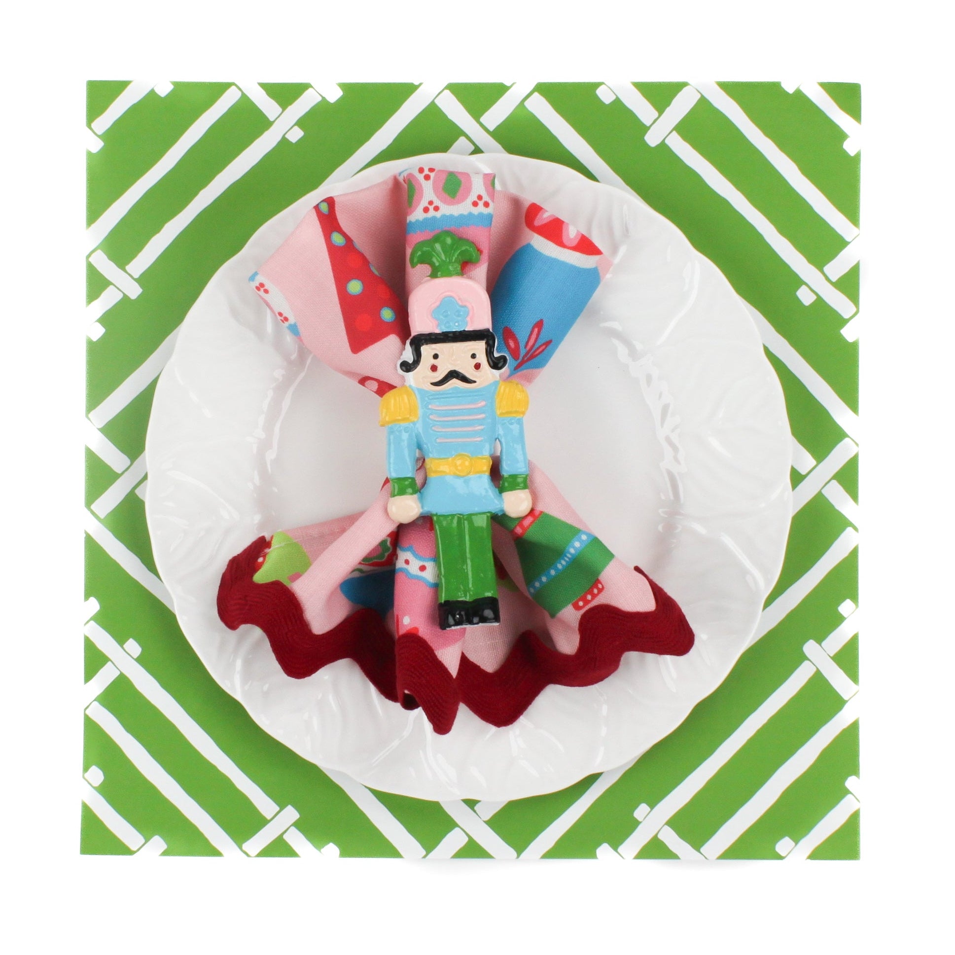 Island House square mid green paper placemats in a white background. A white plate is placed on top of it with a cloth and a nutcraker napkin ring