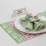Side angle view of Bamboo Trellis Paper Place Card in candy pink displayed on a green and pink Christmas placemat with white plate and decorative napkin.