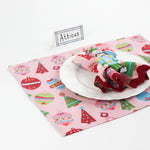 Side angle view of Bamboo Trellis Paper Place Card in navy blue displayed on a Christmas-themed pink placemat with nutcracker napkin and holiday plate.