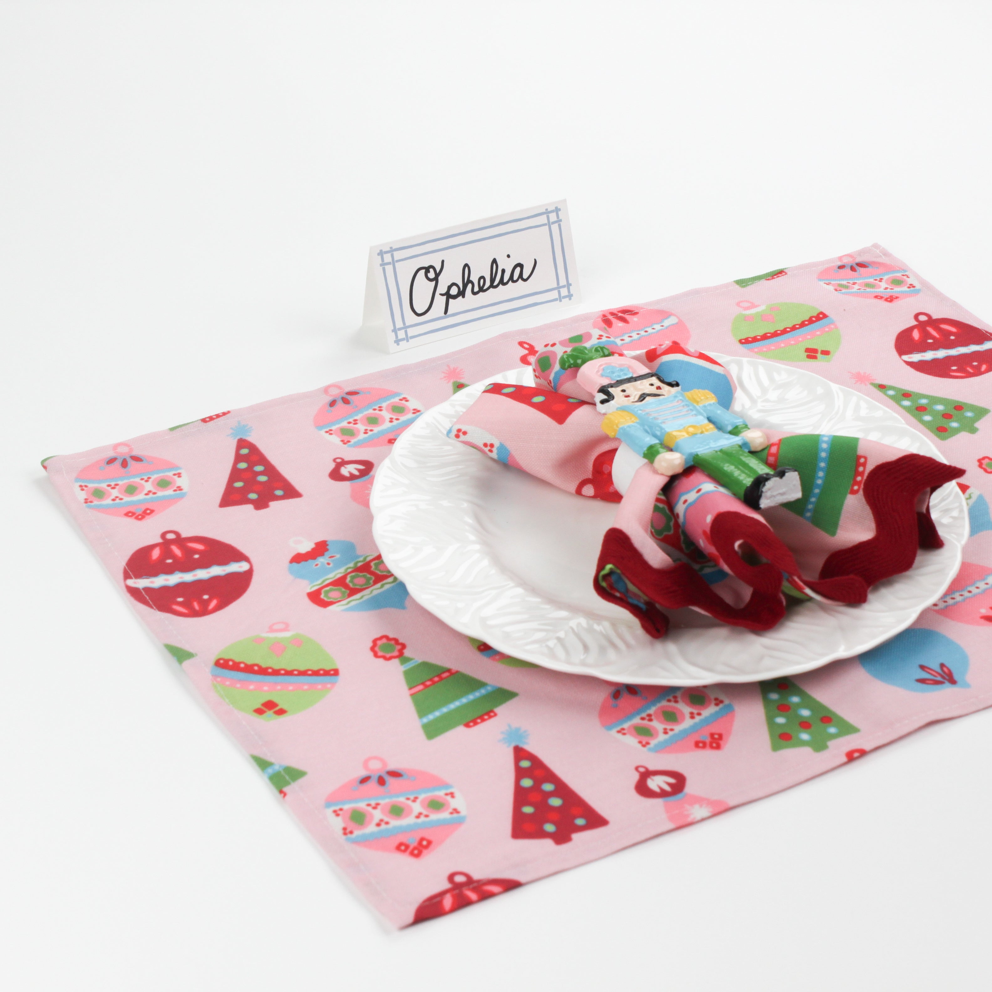 Bamboo Trellis Paper Place Card in pool blue shown on a festive Christmas table setting with pink holiday placemat and nutcracker napkin ring.