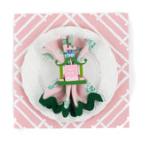pink paper placemats with a white bamboo design called Island house by Madcap Cottage. A white plate is placed on top of it with a cloth and a pagoda napkin ring