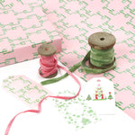 Bamboozled green and pink wrapping paper styled with ribbons and gift tags.
