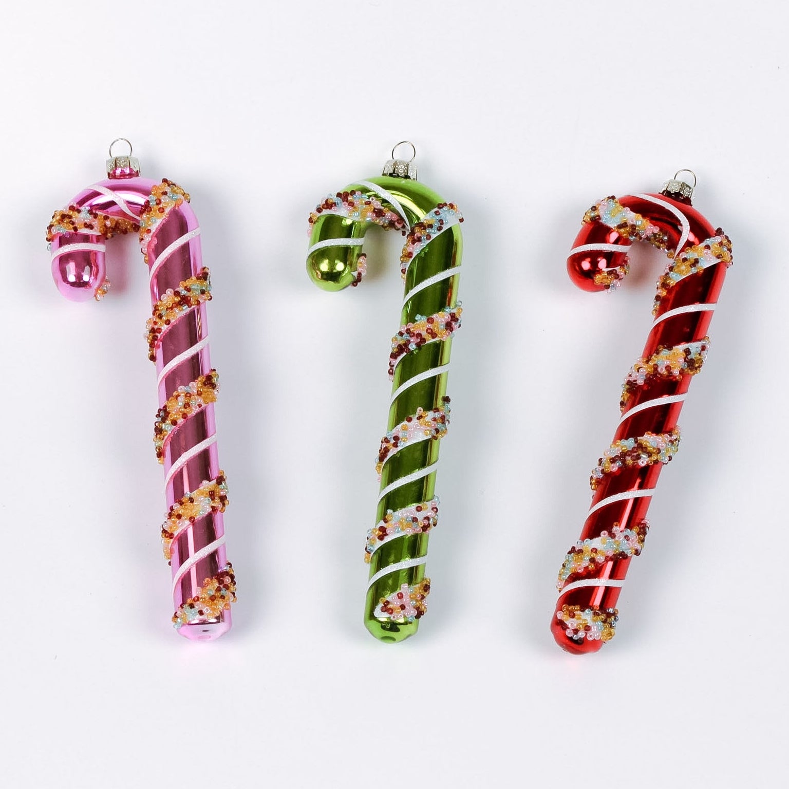 three glass candy cane ornaments on a white background