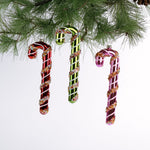 three glass candy cane ornaments on a white background
