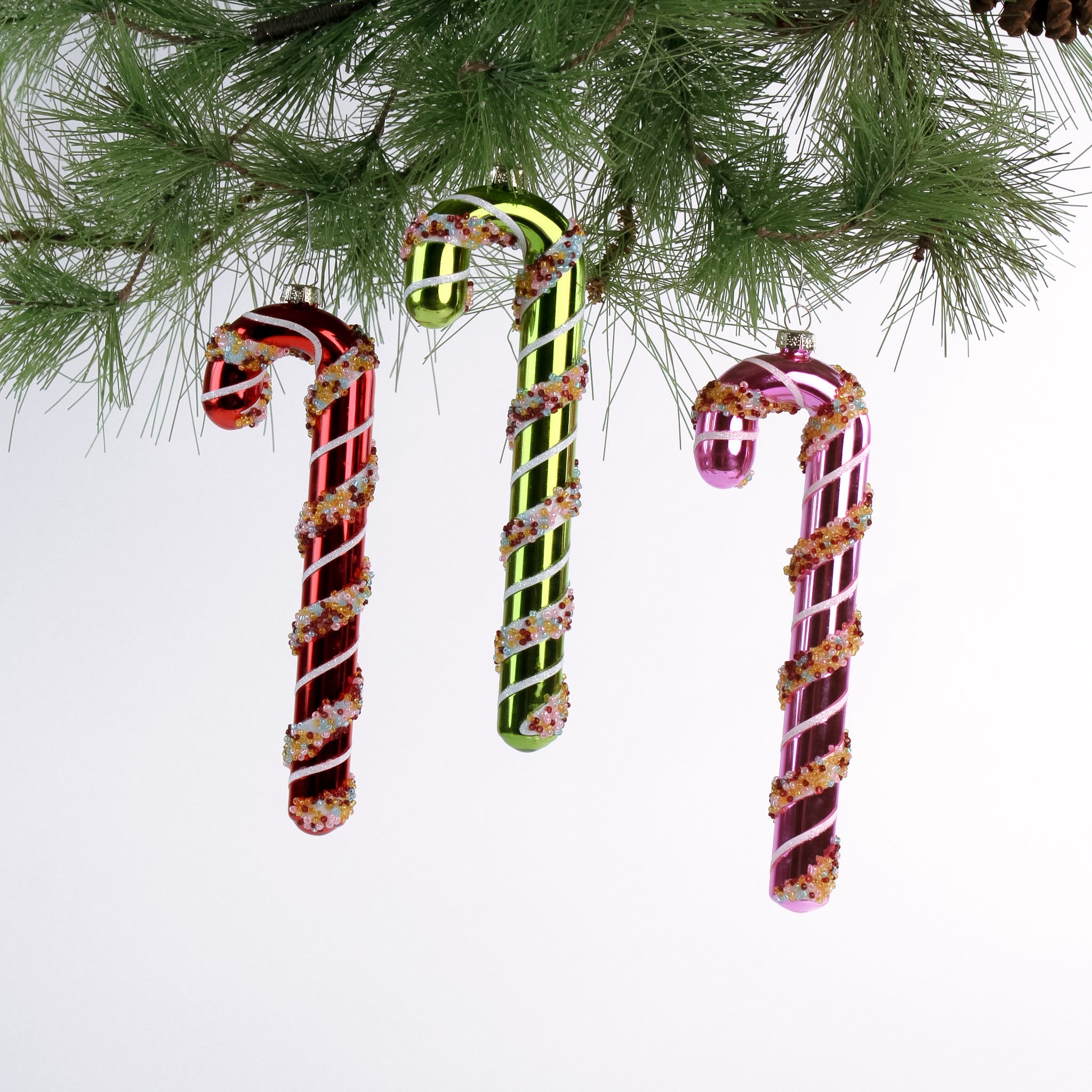 three glass candy cane ornaments on a white background