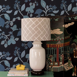 A beige lamp against blue and white wallpaper with lemon and strawberry motifs