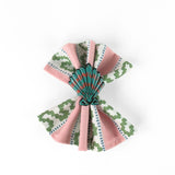 Blue and pink shell napkin ring displayed on a pink patterned cloth napkin.