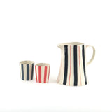 Blue and red striped pitcher with matching striped glasses in cream ceramic with hand painted vertical stripe details.