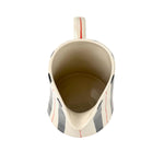 Blue and red striped pitcher top view with cream ceramic interior and curved spout opening.
