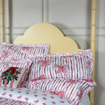 Red and white bow pillows on a bed with a wooden headboard.