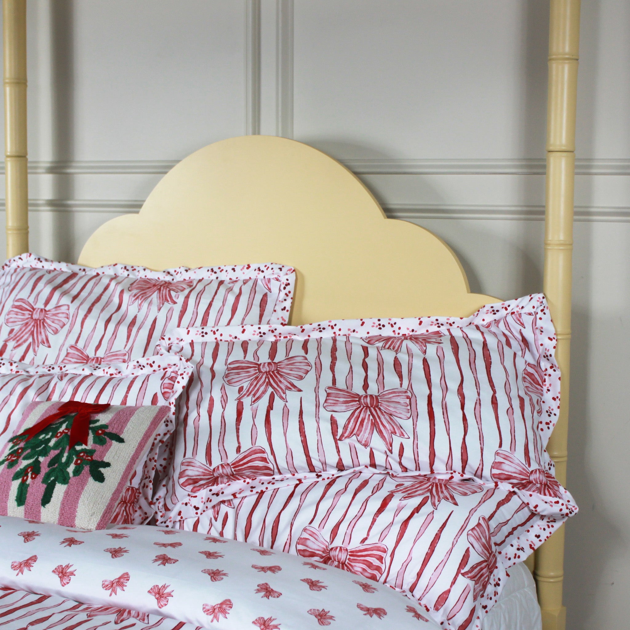Red and white bow pillows on a bed with a wooden headboard.