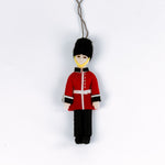 Decorative figure of a British guard in red uniform with black hat on a white background