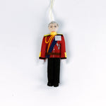 Decorative British Royal Family ornament of a person in a red uniform with a white background