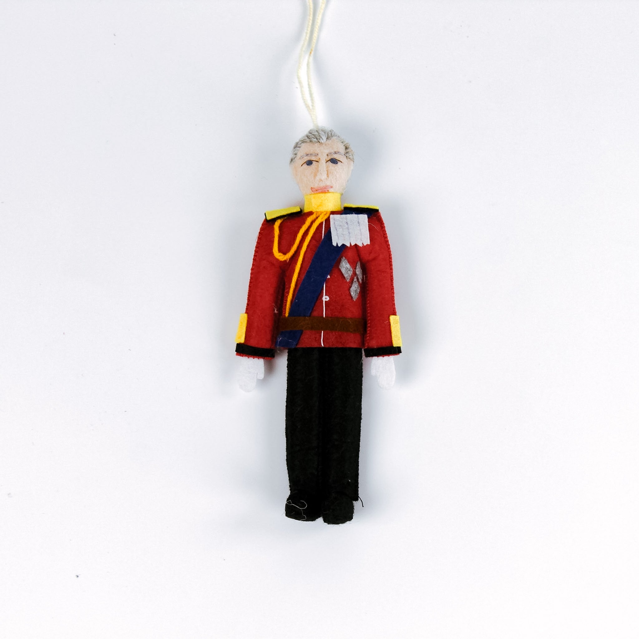 Decorative British Royal Family ornament of a person in a red uniform with a white background