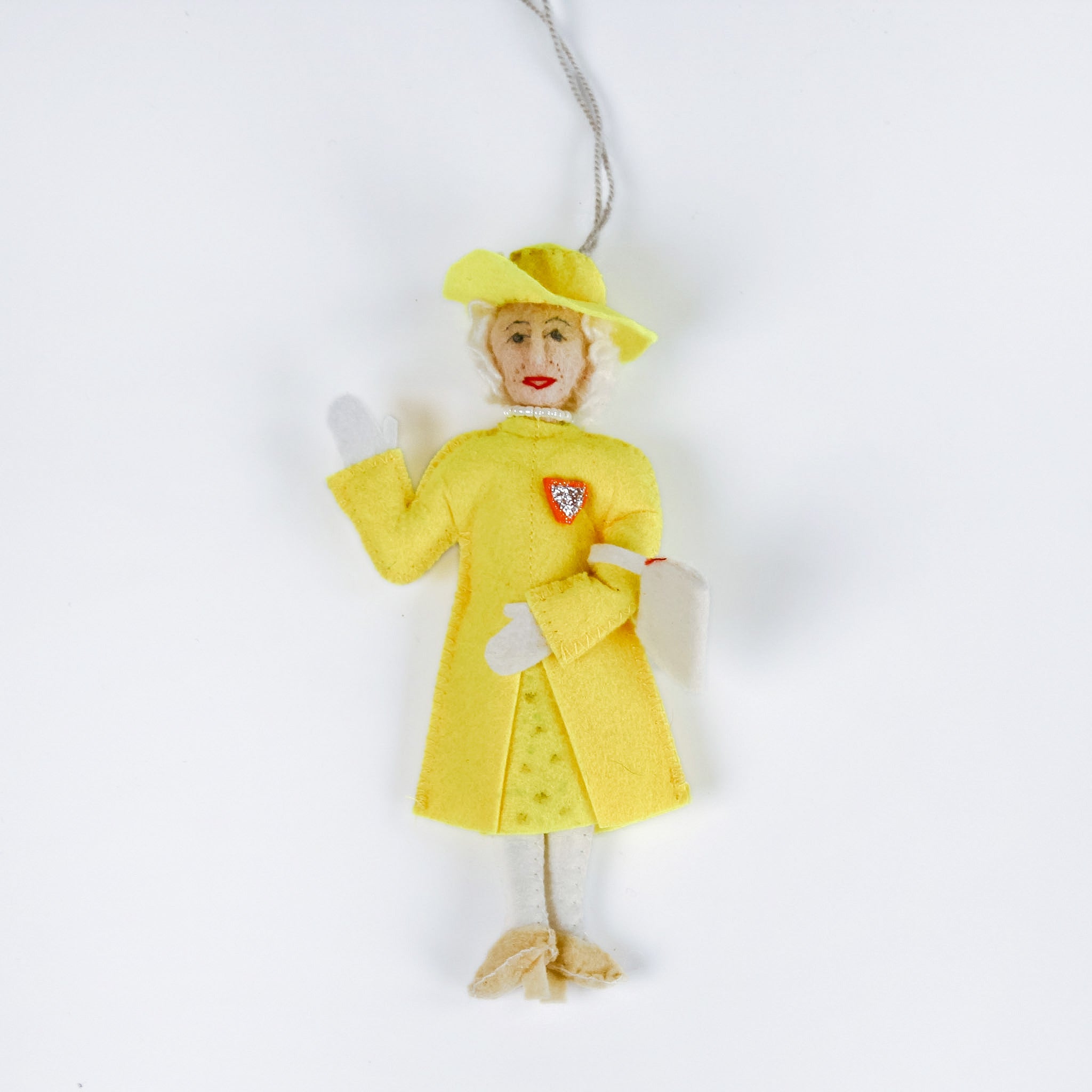 Queen Elizabeth Christmas ornament in a yellow dress with a red heart emblem on a white background