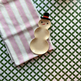 Cabana Boy lavender striped cloth tablecloth with green dashed lines on a white background with a small snowman trinket dish resting on the folded tablecloth