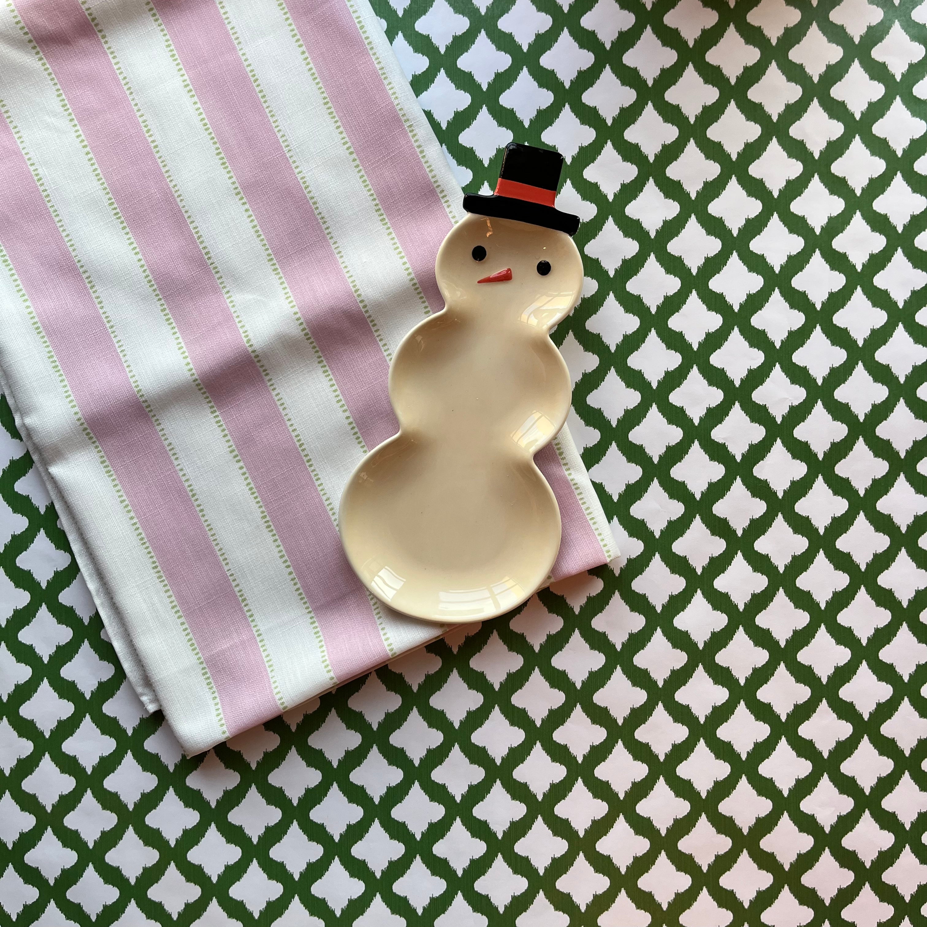 Cabana Boy lavender striped cloth tablecloth with green dashed lines on a white background with a small snowman trinket dish resting on the folded tablecloth