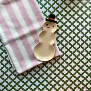 Cabana Boy lavender striped cloth tablecloth with green dashed lines on a white background with a small snowman trinket dish resting on the folded tablecloth