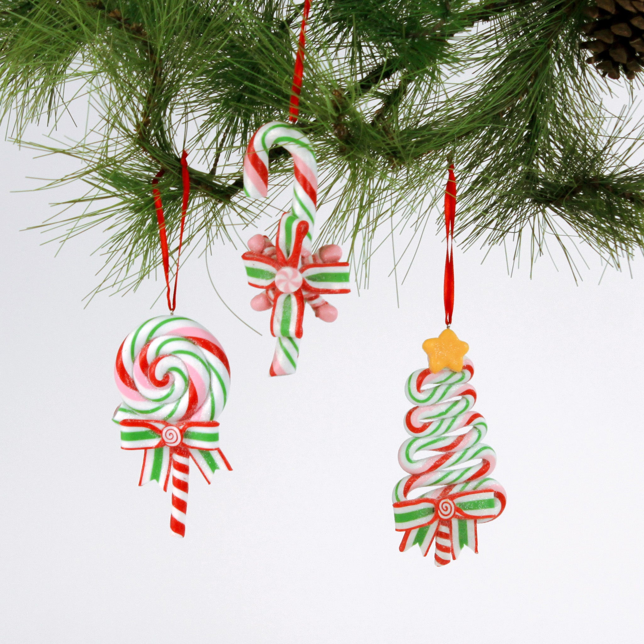 Set of three colorful candy-themed Christmas ornaments shaped like candy canes, lollipops, and Christmas trees