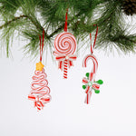 Set of three colorful candy-themed Christmas ornaments shaped like candy canes, lollipops, and Christmas trees