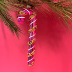 pink glass candy cane ornaments on a pink background