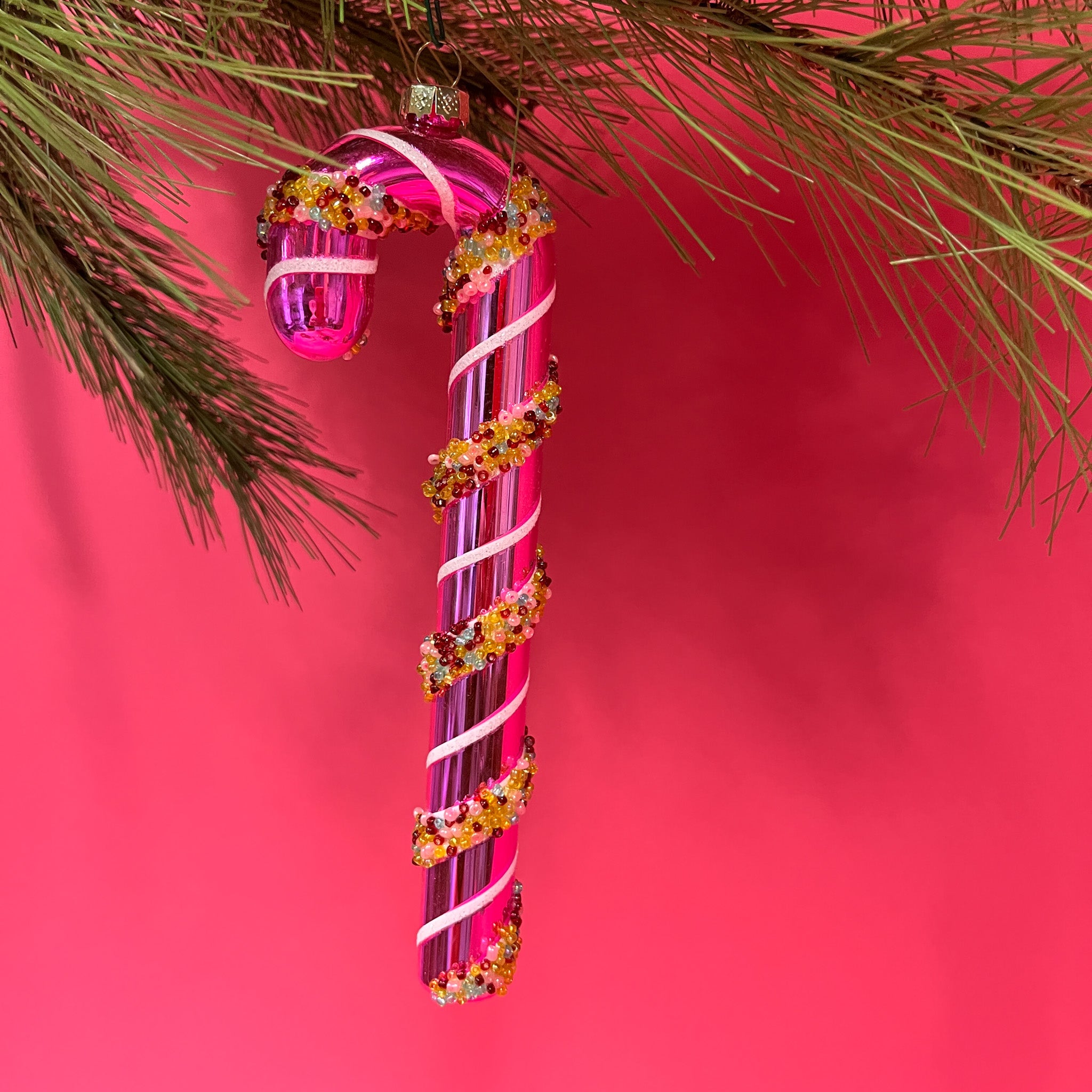 pink glass candy cane ornaments on a pink background