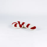 Candy cane–shaped decorative pillow with red and white stripes, made from a textured hooked fabric and laid against a white background.