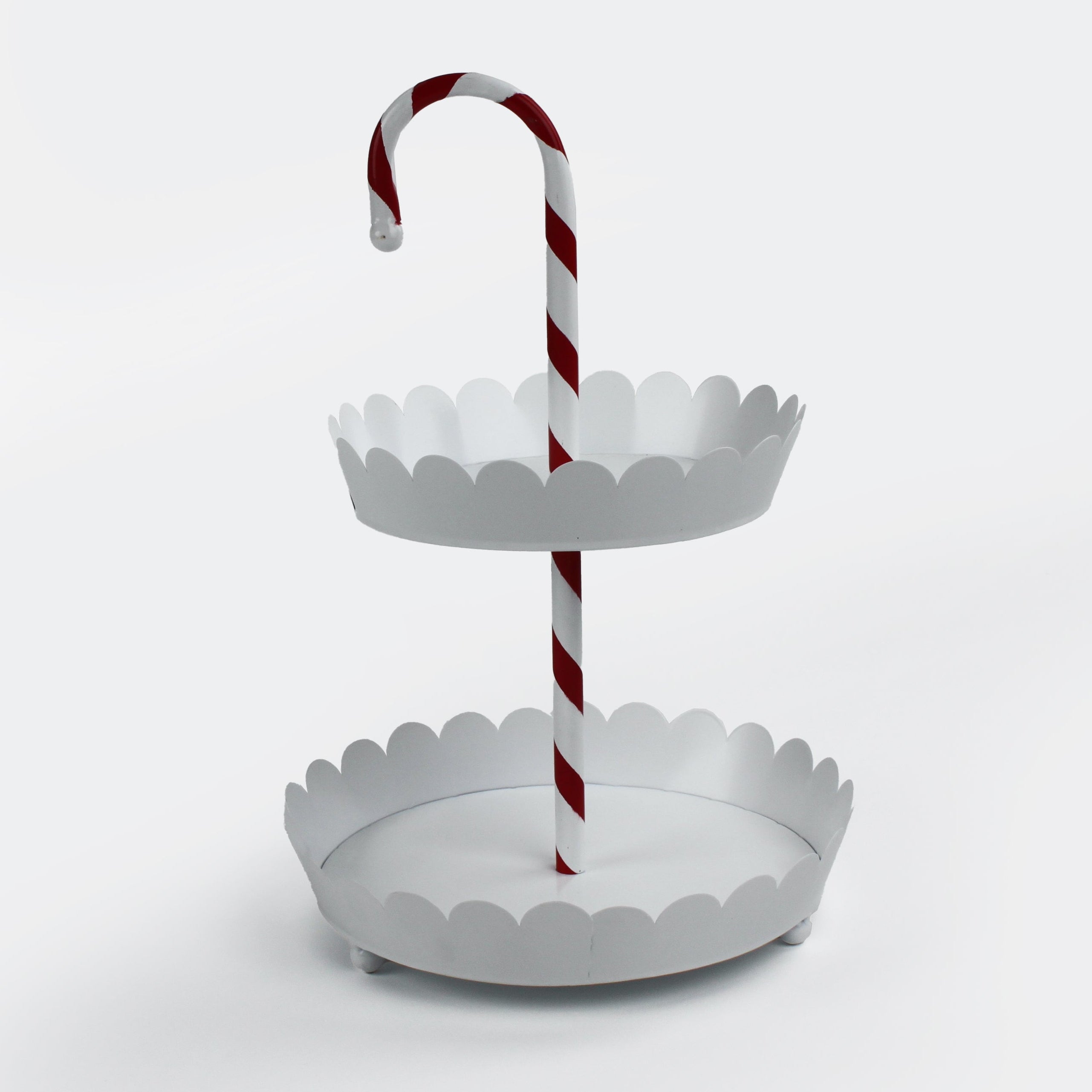 Two-tiered white christmas stand with a red and white striped candy cane center handle on a light gray background