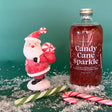 16 ounce glass bottle with red candy cane flavored christmas cocktail and drink mixer with silver edible glitter