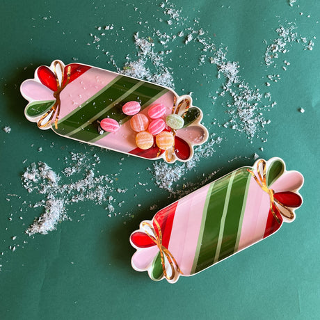Two striped ceramic accent plates with candy motifs on a snowy surface.