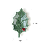 Green holly leaf ceramic dish with red berry detail, shown with measurements 7.75 inches tall and 4.5 inches wide on a white background.