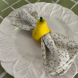 Ceramic pear napkin rings in yellow with green stem, styled with patterned cloth napkins