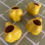 Ceramic pear napkin rings in yellow with green stem, styled with patterned cloth napkins