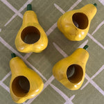 Ceramic pear napkin rings in yellow with green stem, styled with patterned cloth napkins