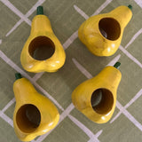Ceramic pear napkin rings in yellow with green stem, styled with patterned cloth napkins