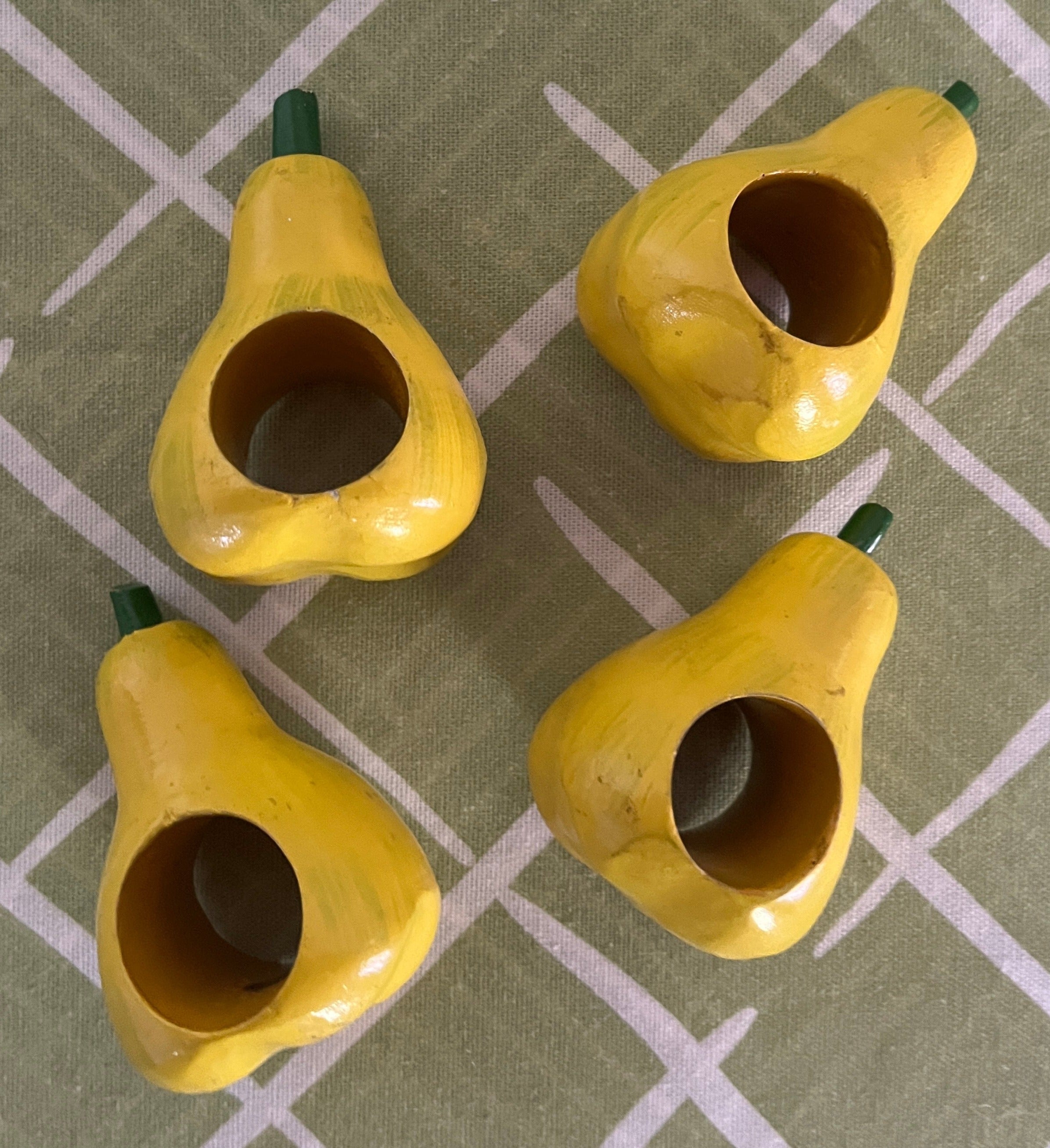 Ceramic pear napkin rings in yellow with green stem, styled with patterned cloth napkins