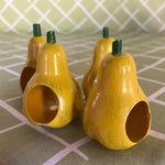 Ceramic pear napkin rings in yellow with green stem, styled with patterned cloth napkins