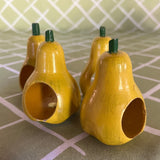 Ceramic pear napkin rings in yellow with green stem, styled with patterned cloth napkins