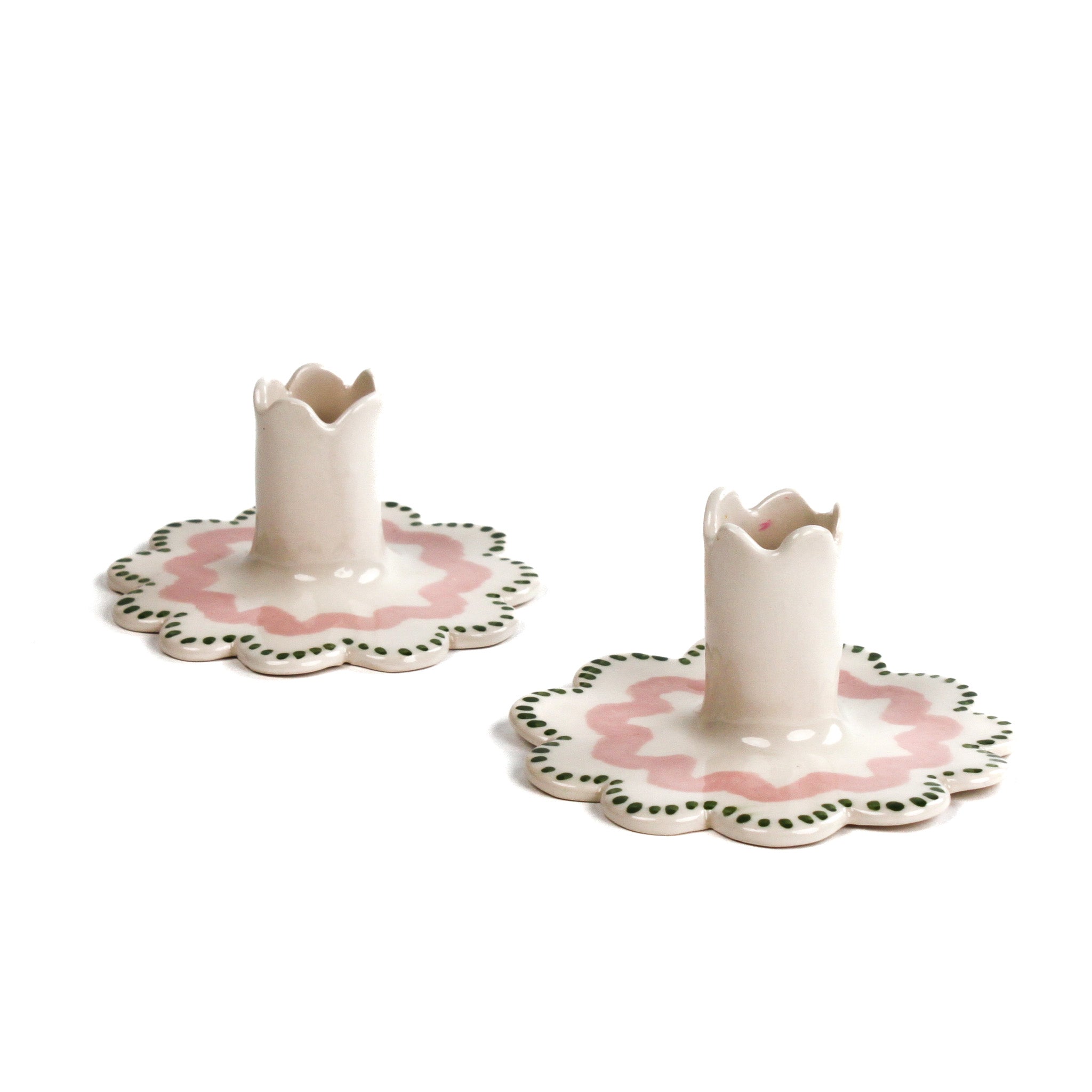 Set of two hand-painted ceramic scalloped candle holders with pink floral detailing and green dotted trim, designed for taper candles, displayed on a white background.
