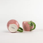 2 pink Ceramic Strawberry Mugs with green handler in a white background, showing the bottom part