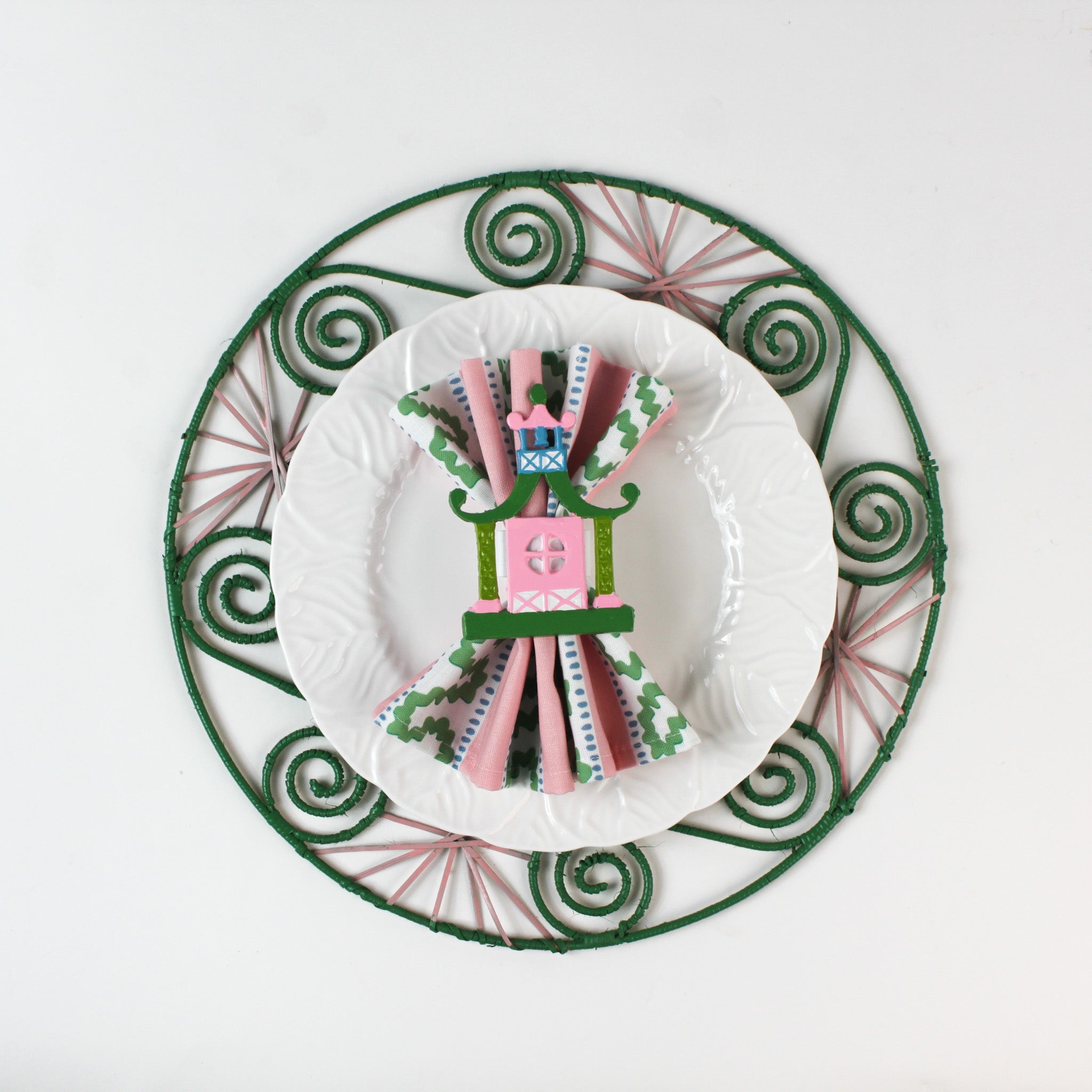 Chinoiserie Pagoda Painted-Metal Napkin Rings with one on a pink, green and white plate dinner napkin
